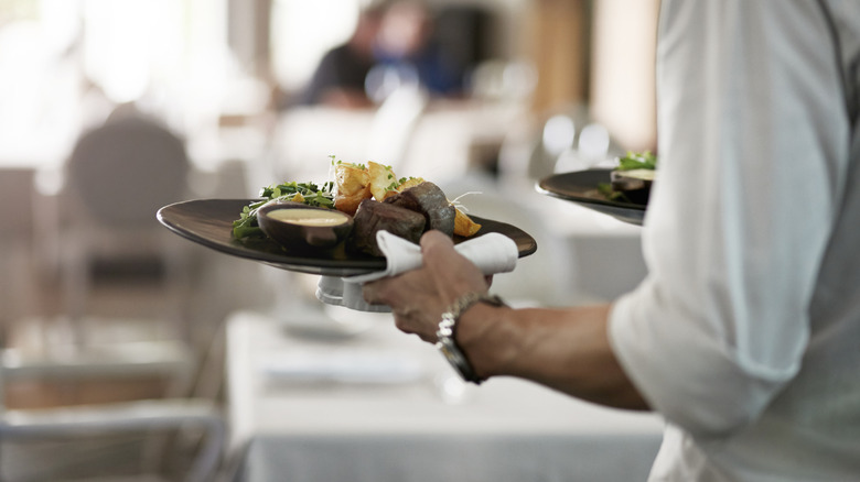 Waitstaff carrying meal plates at an upscale restaurant