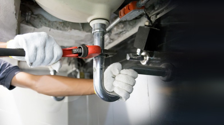 A technician repairing a pipe under the sink.