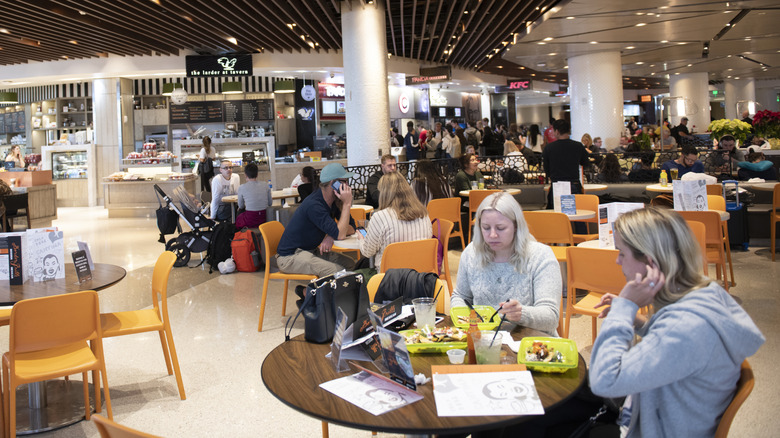 People eating at tables in an airport.