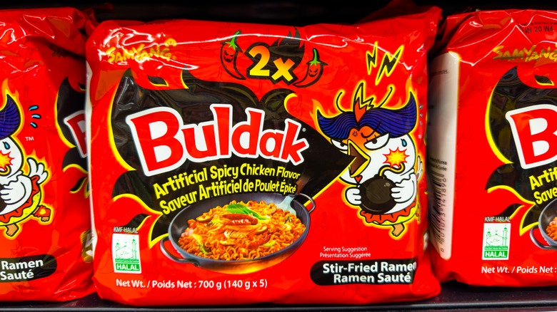 A package of Buldak 2x spicy chicken noodles on a supermarket shelf.