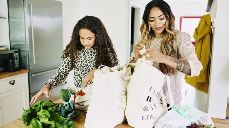 woman and child unpacking groceries from reusable bags