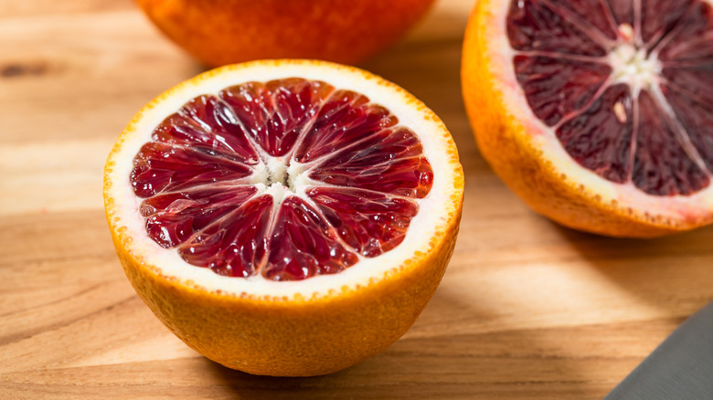 A blood orange is halved to reveal its ruby interior.