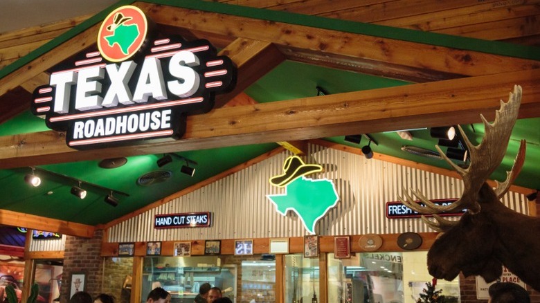 The interior of a typical Texas Roadhouse restaurant with a sign for hand cut steaks on the wall.