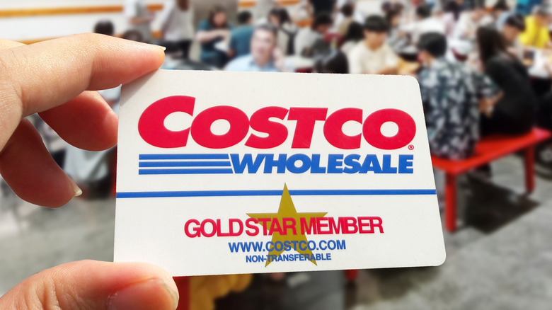 Hand holding up Costco membership card inside the store