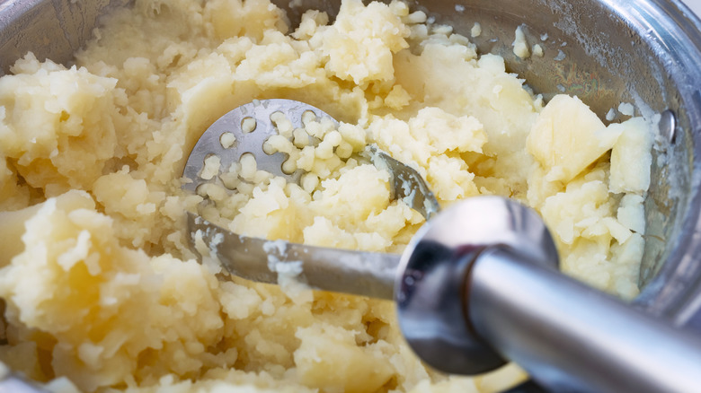 Mashing potatoes in a pot.