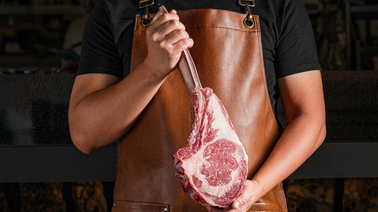Butcher holding a tomahawk steak