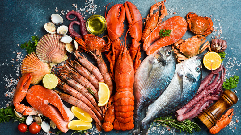 A wide variety of fresh seafood displayed on surface with herbs and seasonings.