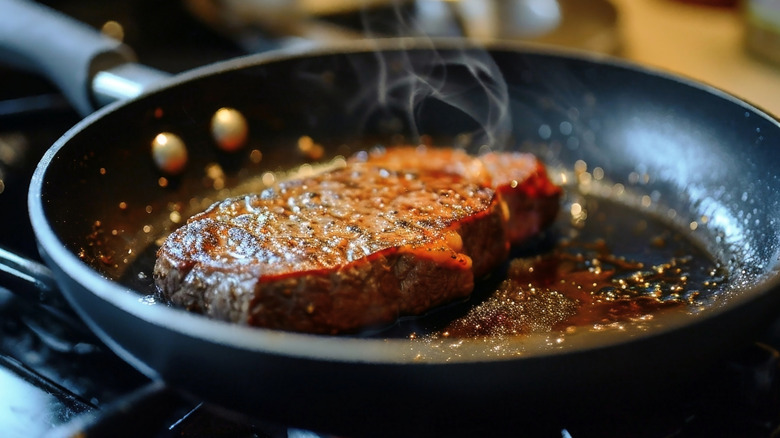 A steak being seared in a pan