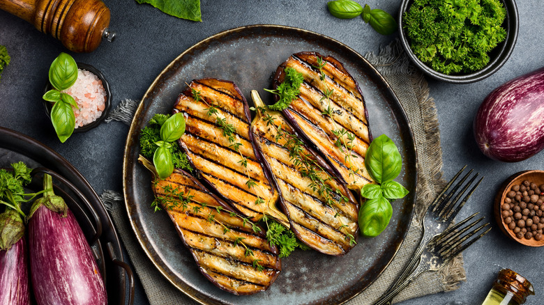 long slices of grilled eggplant on a black plate
