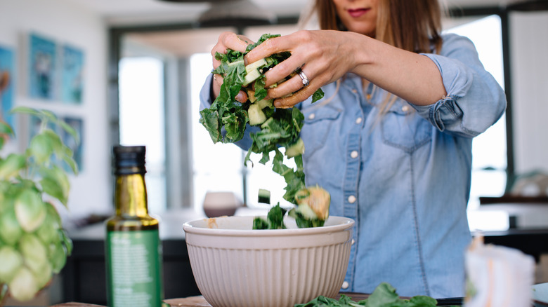 woman preparing salad in bowl