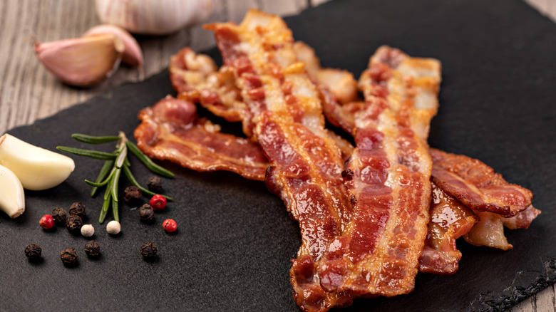 Well-done bacon strips, beautifully presented with garlic cloves and assorted spices