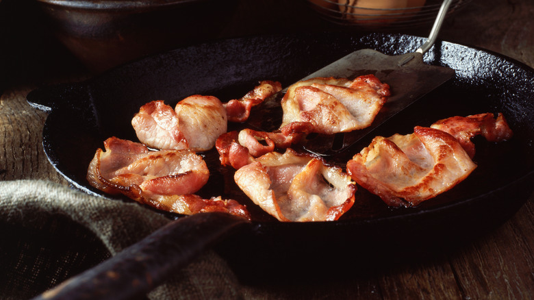 Bacon frying in a pan on a stove