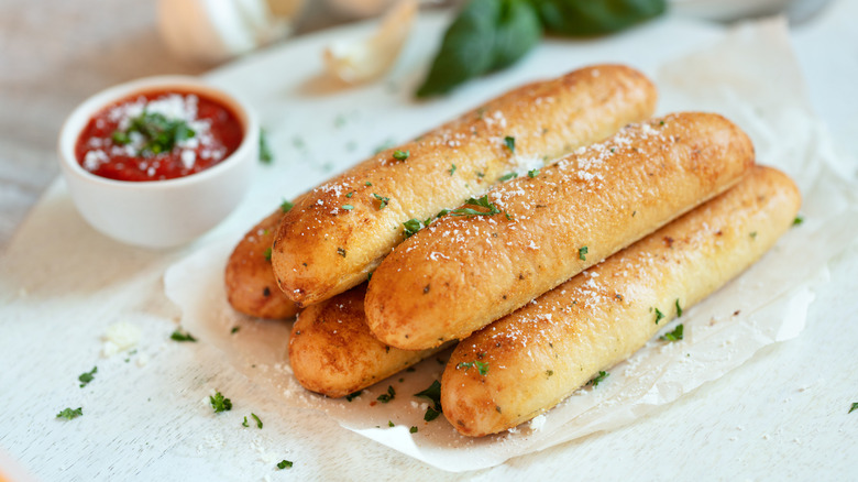 Breadsticks on paper with a bowl of marinara