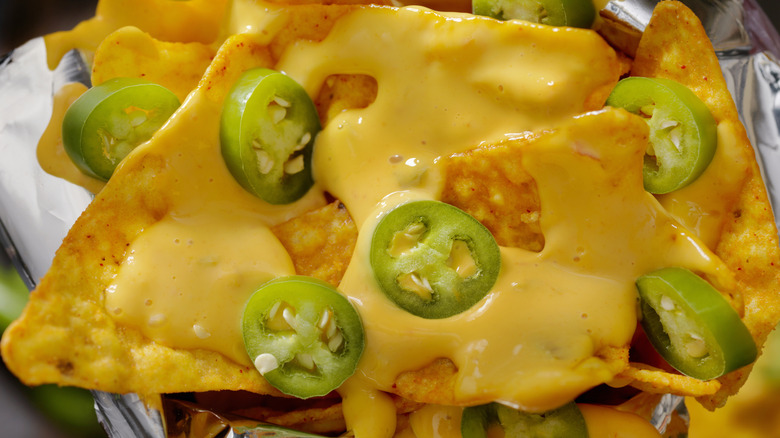 Tortilla chips covered in nacho cheese and jalapeno slices.
