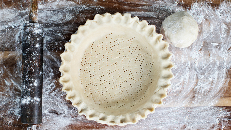 Raw pie dough shaped into a crust on a table with flour.