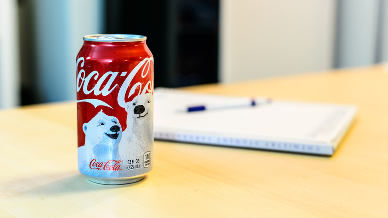 Can of Coca-Cola with a polar bear winter design on a desk next to a notebook