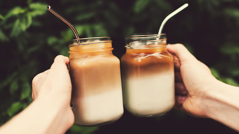 Clinking glasses of cold coffee with straws