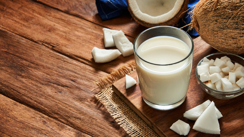 glass of coconut milk beside coconut pieces