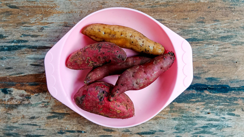 Boiled purple sweet potatoes in a plate on a wooden background.