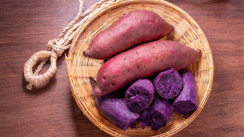 Purple sweet potatoes in a basket on a wooden background.
