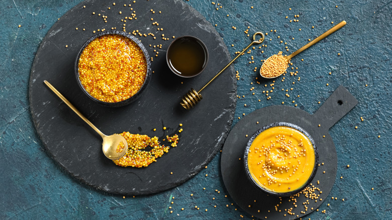 A couple bowls of mustard with honey on the side