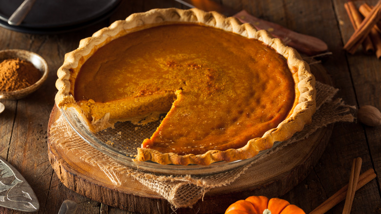 plain pumpkin pie in a dish with a slice cut out of it