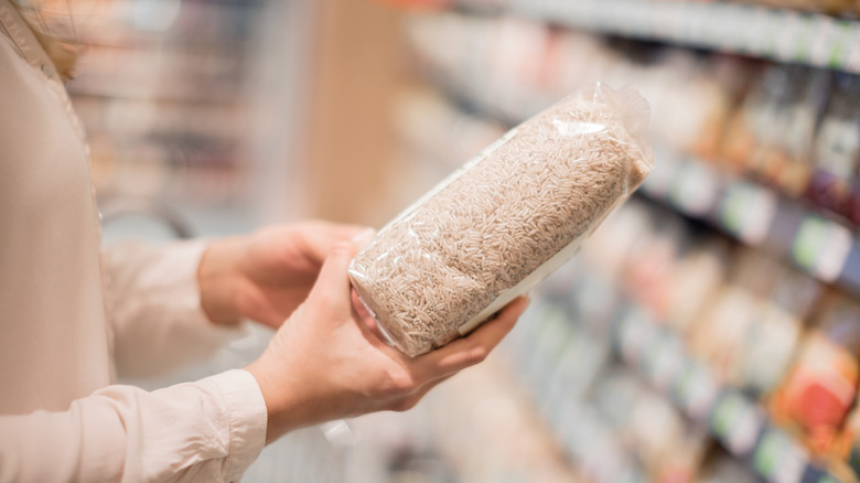 Person holding a package of rice in a grocery store