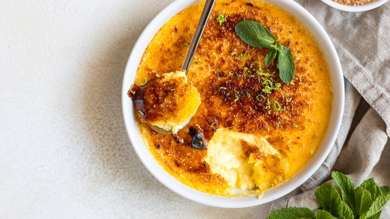 A cracked crème brûlée with a spoonful removed is photographed from overhead.