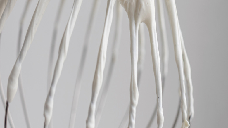 Close-up of a wire whisk with soft peaks of whipped cream
