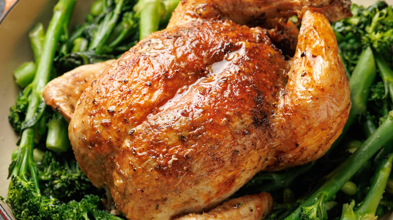 A close up of roasted chicken sitting atop fresh greens