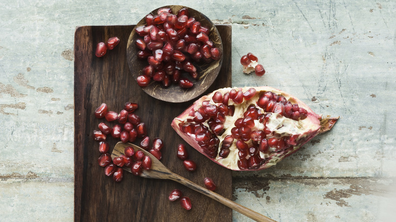 pomegranate and seeds on wooden board