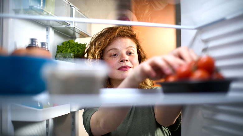 woman reaching into fridge