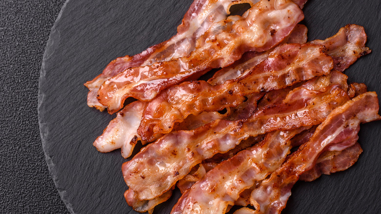 Several pieces of cooked bacon on a black plate