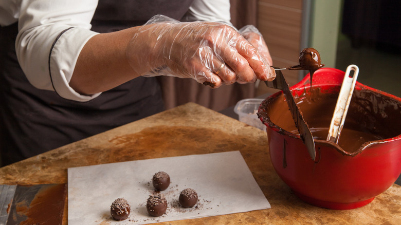 Person dipping truffles into tempered chocolate