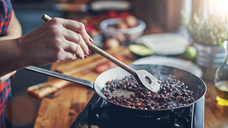 Black beans cooking in a skillet on the stove. Perfectly cooked and ready to be used in huevos rancheros.