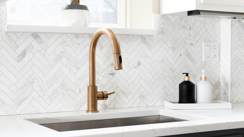 sink detail with a white herringbone tile backsplash