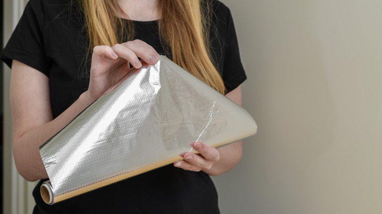 Woman opening a roll of aluminum foil