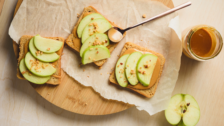 Peanut butter and apples topped with chopped nuts on bread