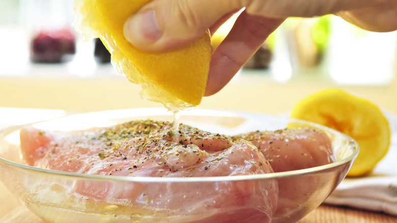 Squeezing lemon over raw chicken