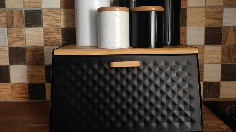 A small cabinet on a kitchen counter, itself topped with canisters.