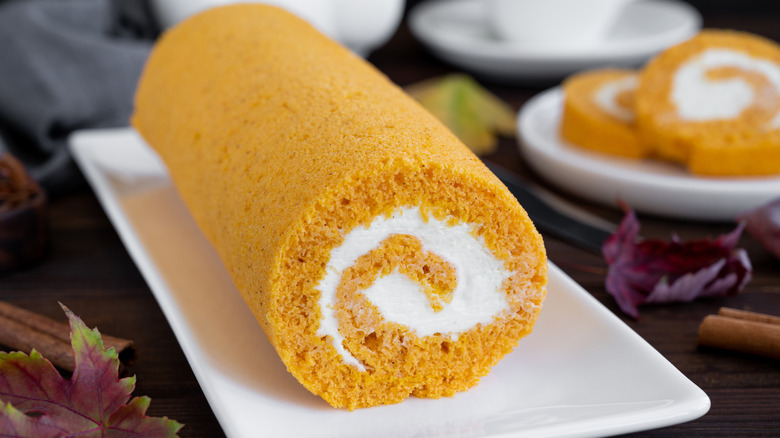 Pumpkin roll on a white tray next to fall decorations