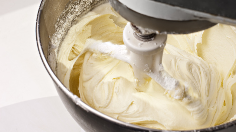 A Kitchen Aid mixer with a bowl filled with whipped cream cheese frosting