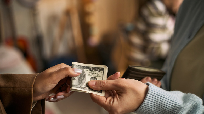 One person handing folded money to another person