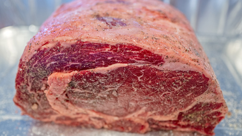 Close-up of a prime rib covered in salt and pepper