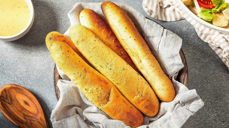 Soft breadsticks in a wooden bowl with a cloth napkin
