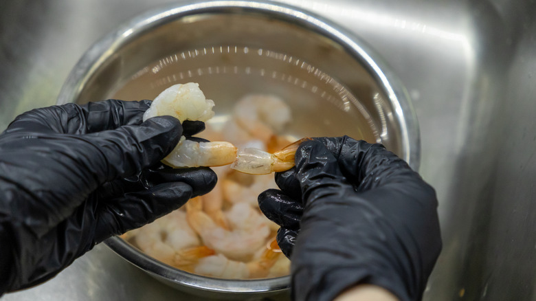 An illustrative image showing a person cleaning raw shrimp.