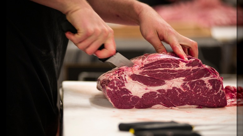 A person cutting a piece of chuck roll