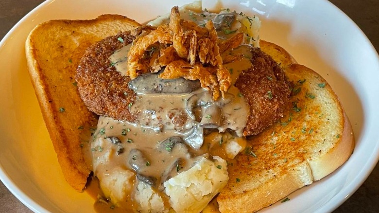 Stack of toast, mashed potatoes, fried Salisbury steak, mushroom gravy, and fried onions