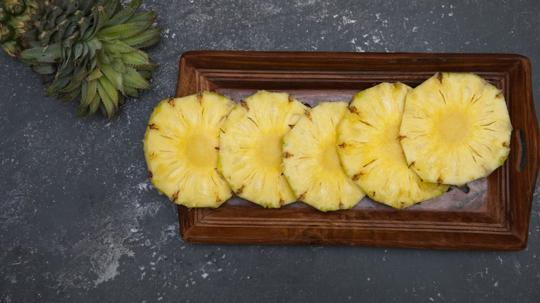 Pineapple slices on a wooden tray.