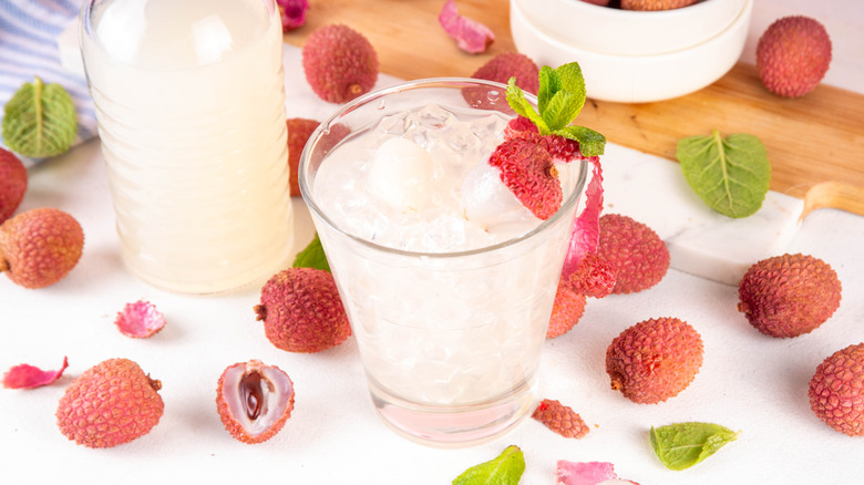 Glass of lychee juice with lychee fruit surrounding